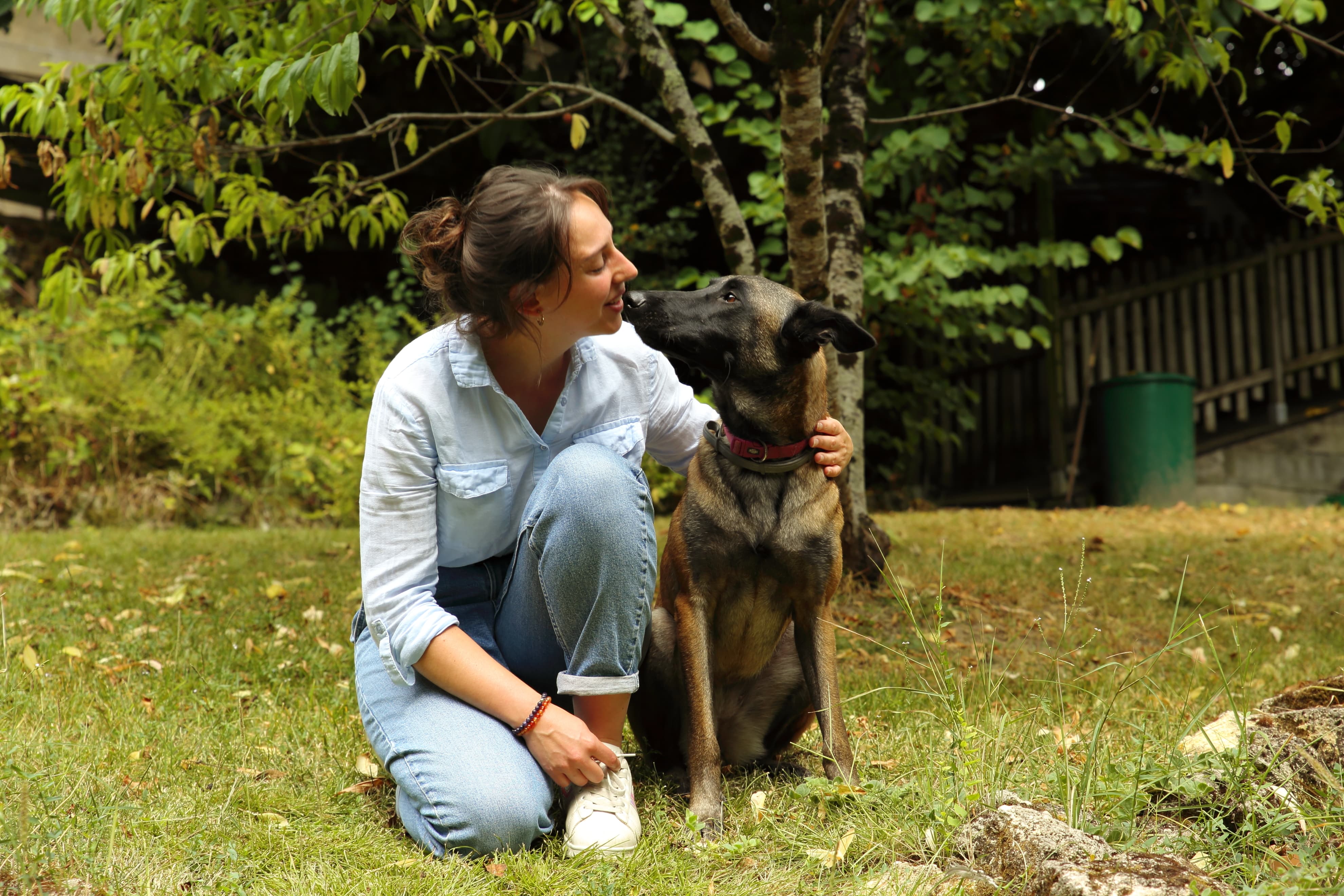 Tika, le chien, et Camille s'échangeant un bisou, capturant un moment de tendresse et de complicité entre l'éducatrice canine et son animal